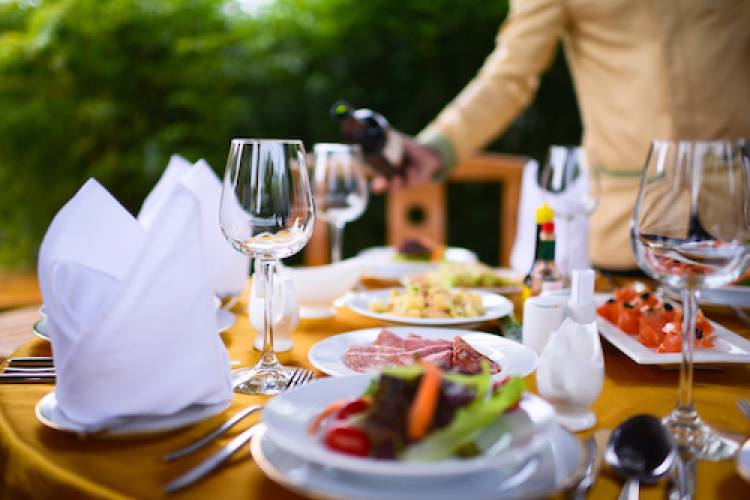 waiter pouring wine into a glass at a beautifully set table