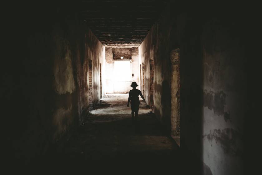 creepy view of shadowed child at end of long hallway